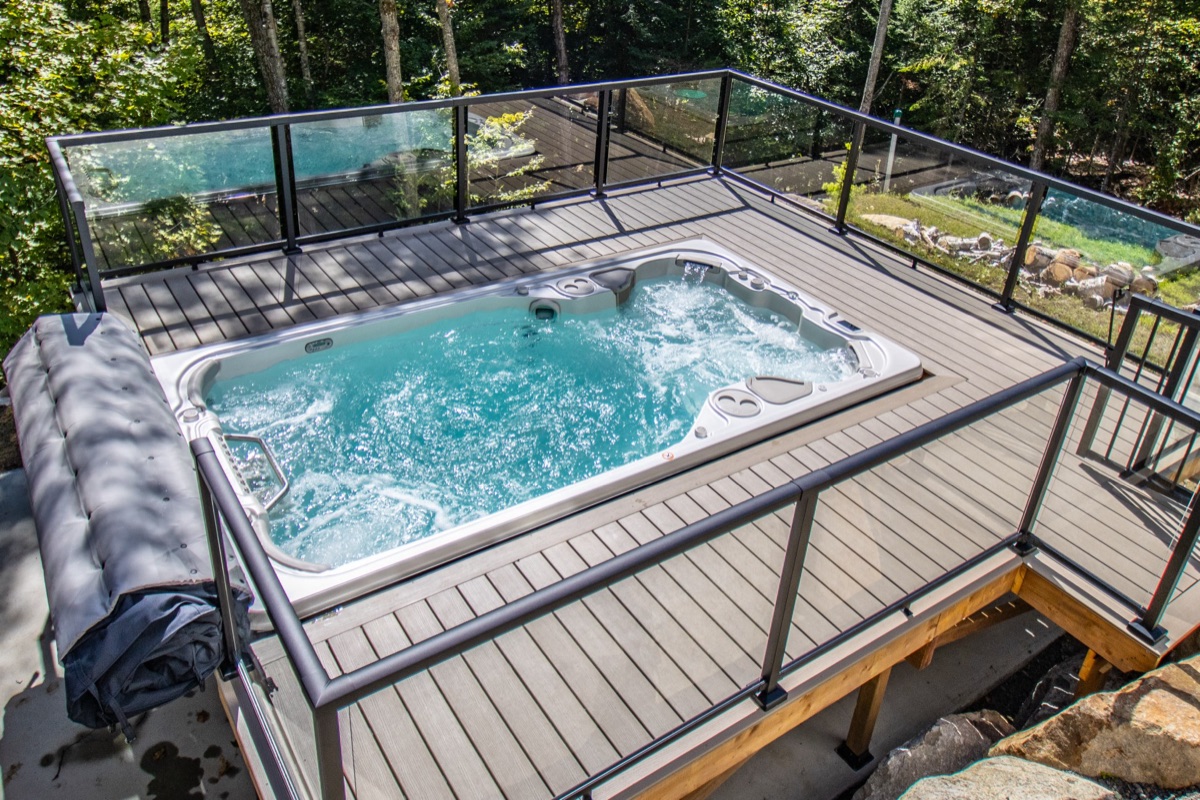 Hydropool Signature Collection hot tub on a backyard deck with glass railing
