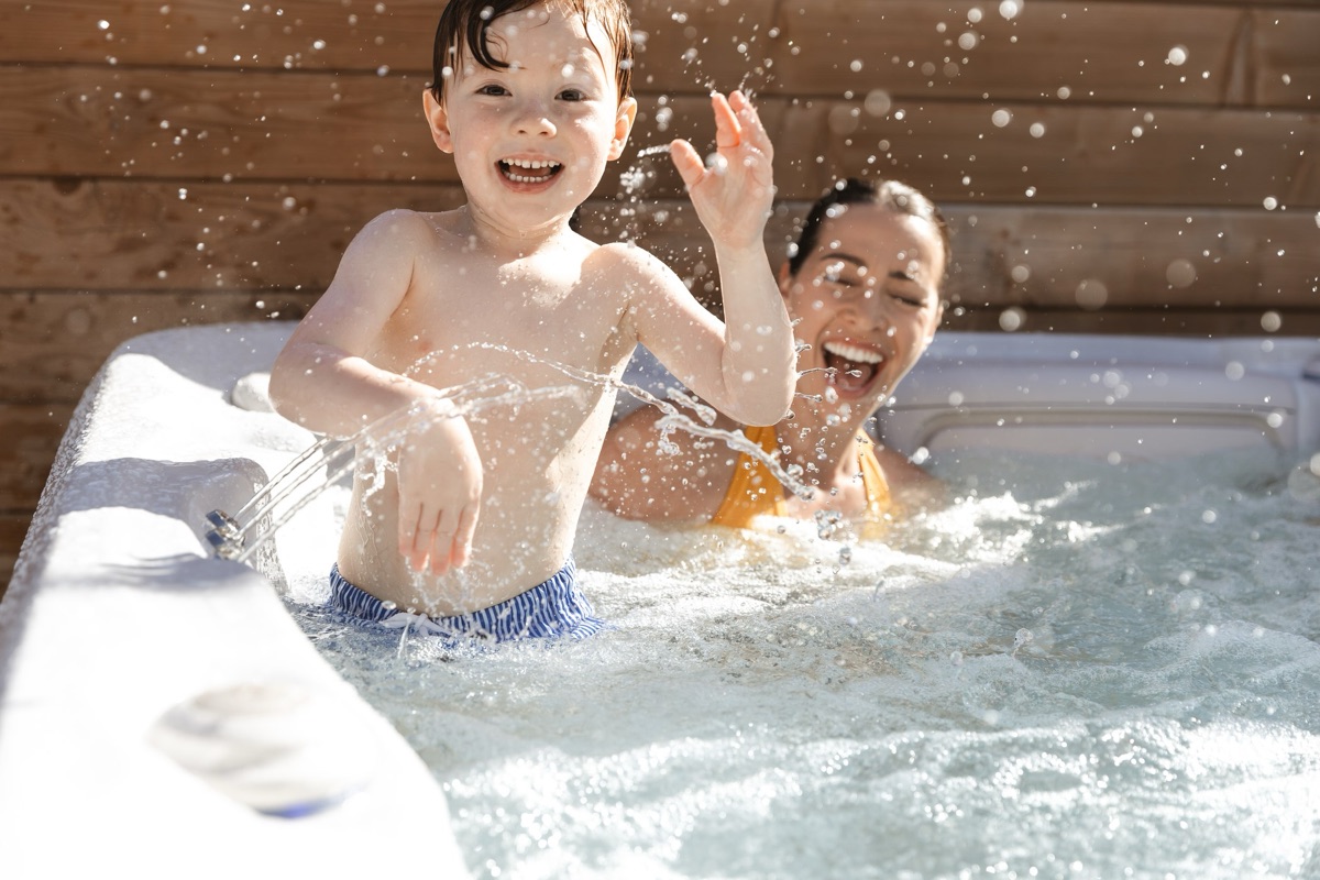 Family laughing and splashing in a Hydropool Serenity hot tub
