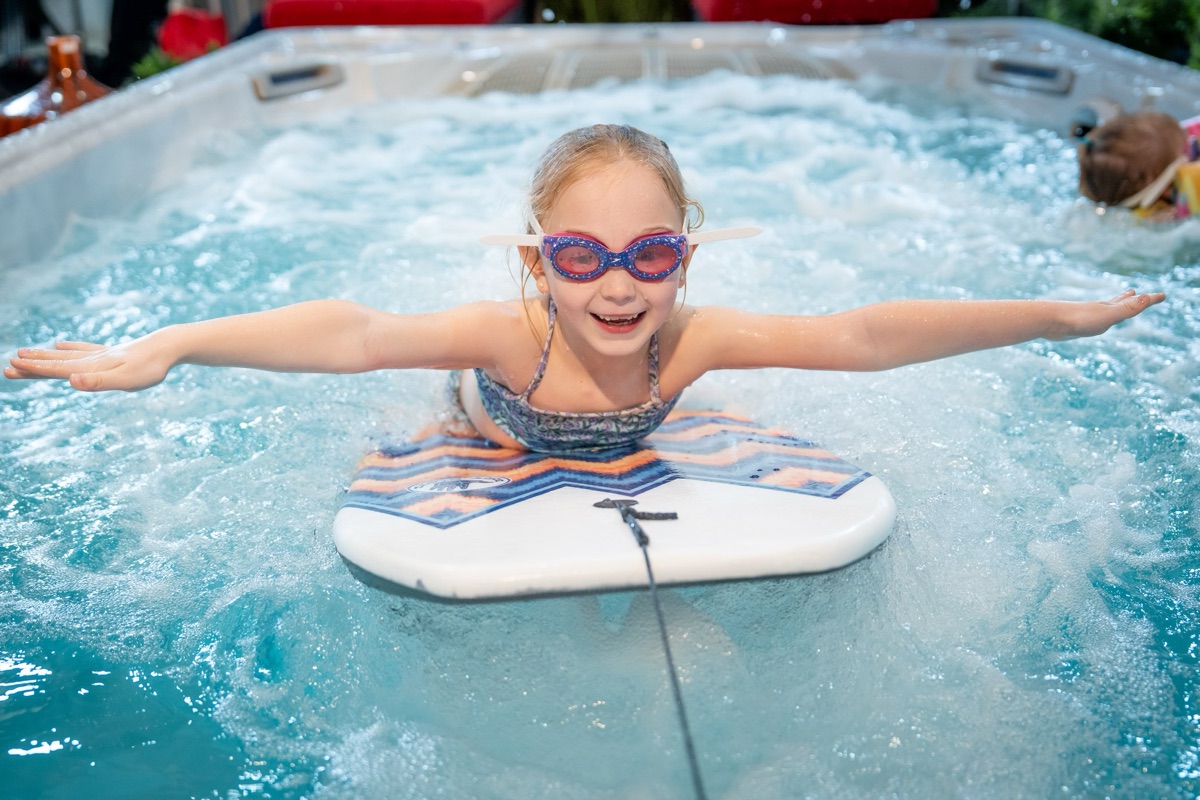 Child swimming with a kickboard against the current in a Hydropool swim spa