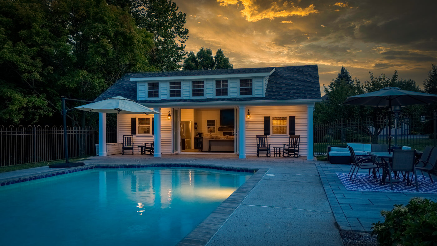 Heritage pool house with white clapboard siding, covered porch, french doors