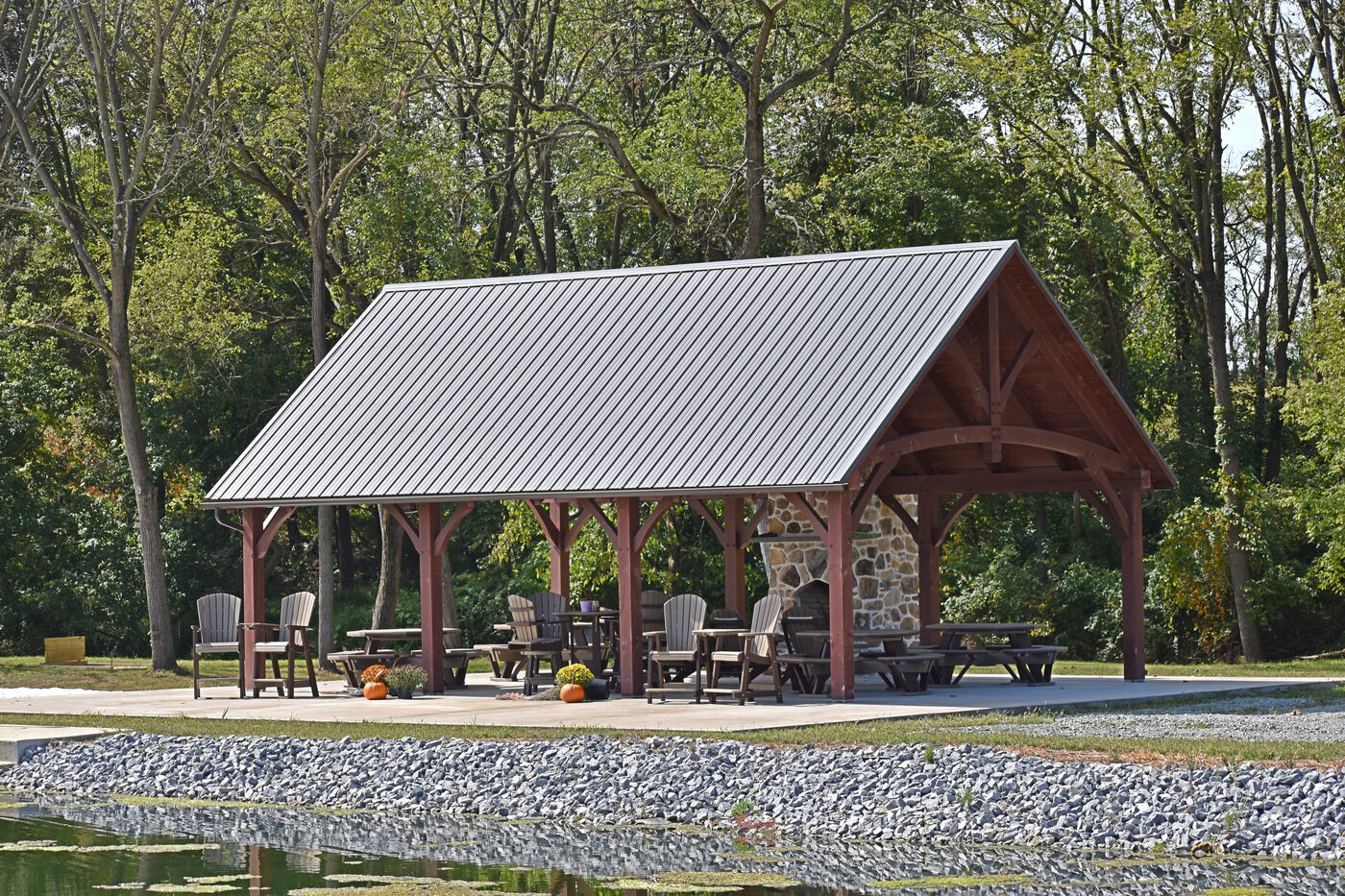 Homestead Timber Frame pavilion with metal roof, exposed timber trusses, and stone fireplace
