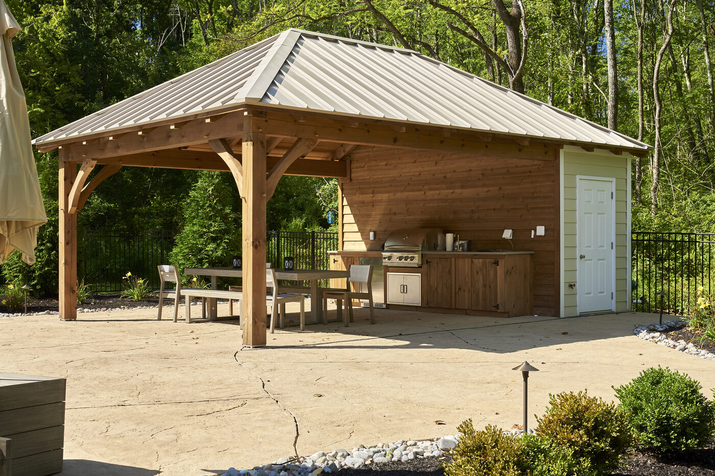 Custom Homestead timber-frame pool house with cypress siding, bronze standing seam metal roof, exposed timber interior, stone fireplace