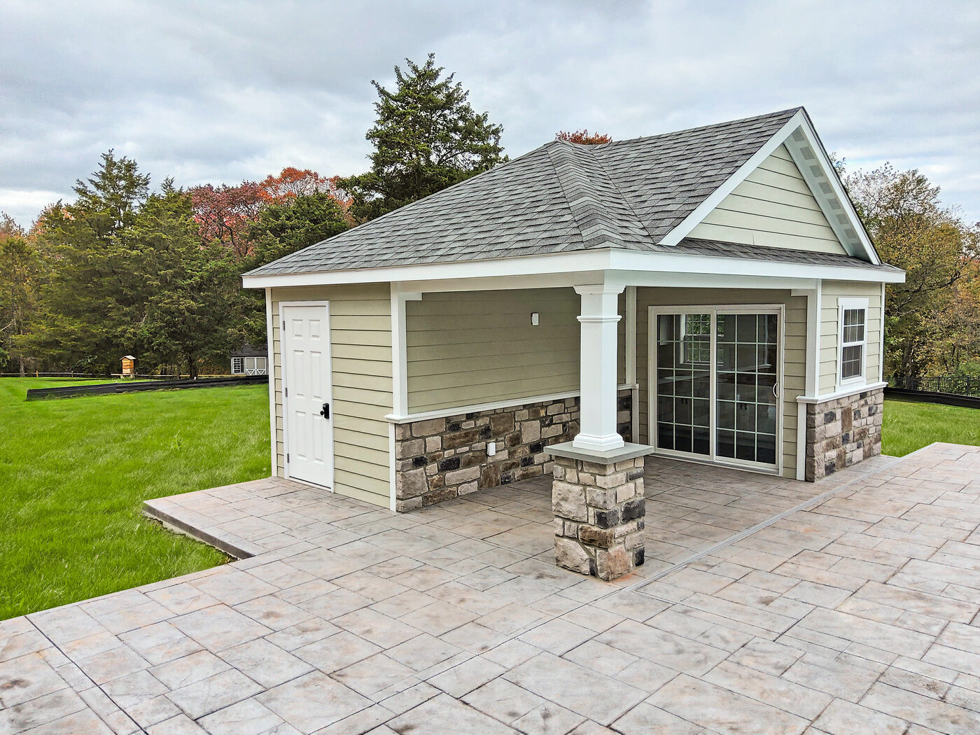 Homestead Wellington pool house with stucco siding, granite bar counter, white trim, covered porch entry beside a pool